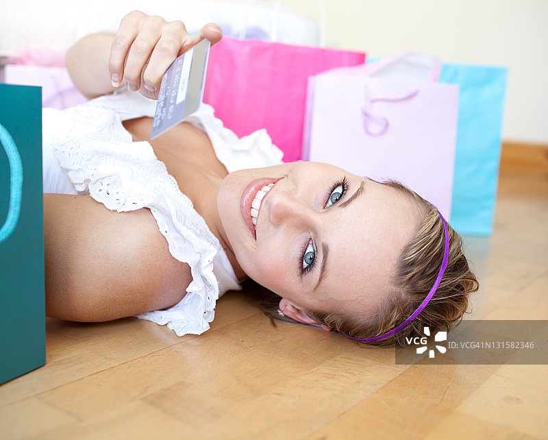 微笑的女人躺在地板上拿着信用卡图片素材