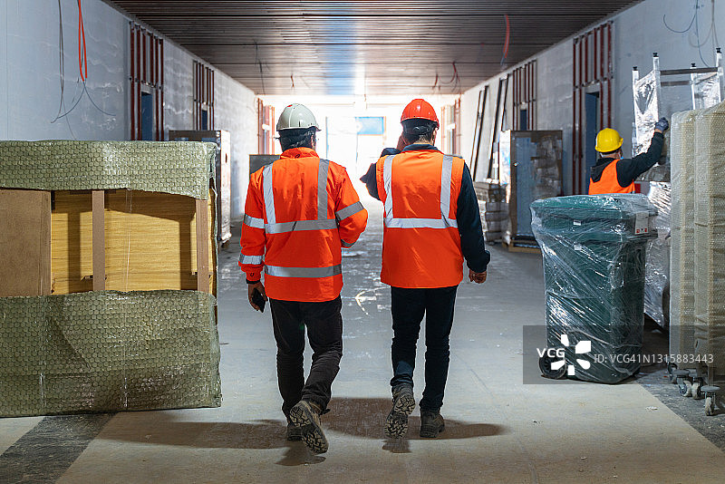 两名工程师穿着防护工作服走在建筑工地上图片素材