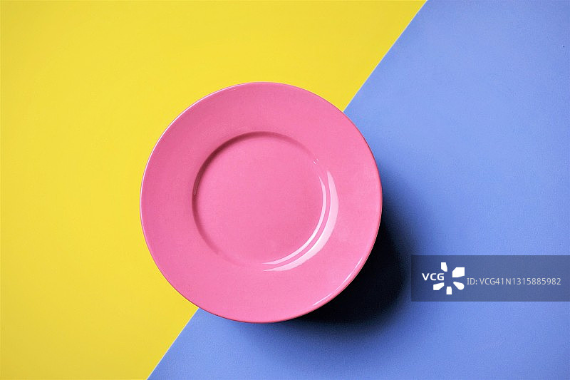 蓝色和黄色背景上的粉色盘子图片素材