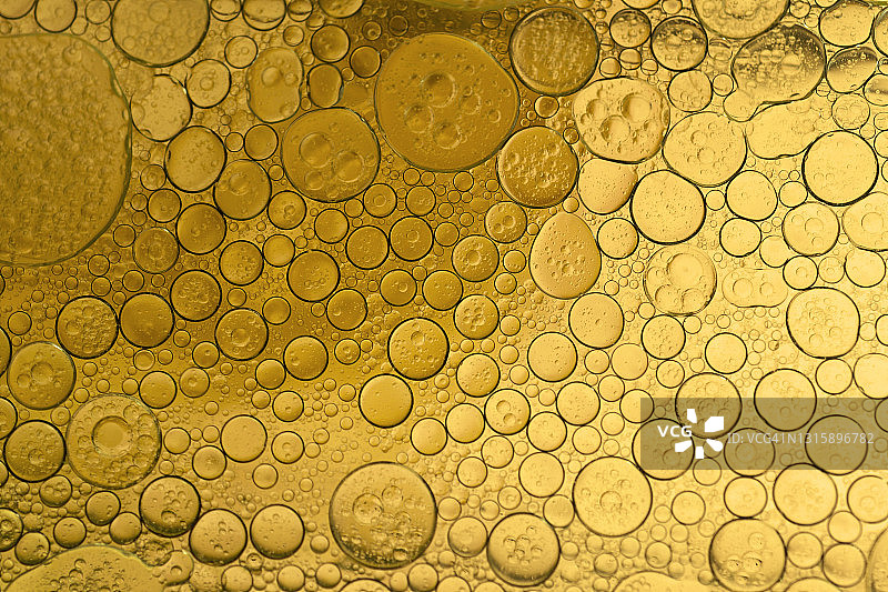金色液体上气泡和油滴形成的抽象形状和纹理图片素材