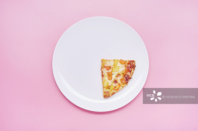 粉色背景下盘子里的一小块披萨俯视图图片素材