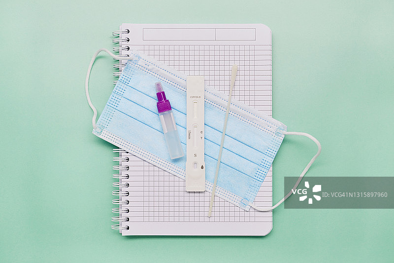 用于新冠病毒检测（COVID-19）的外科口罩、棉签和试管俯视图图片素材