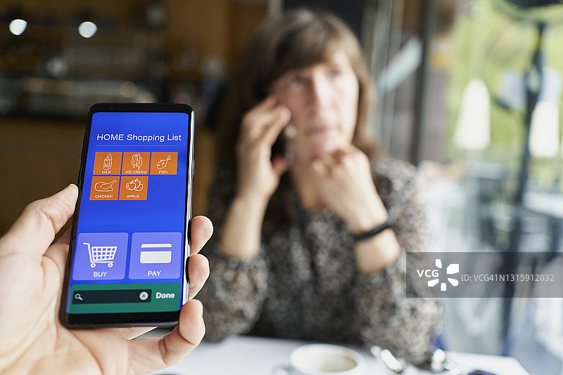 在自助餐厅内手持智能手机，使用App在超市购物图片素材