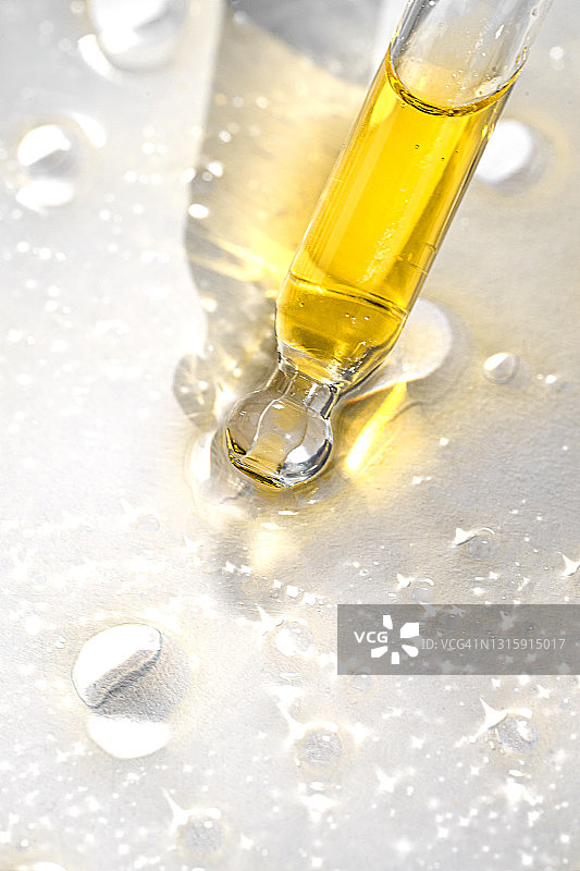 具有透明黄色液体和纯净水或天然油滴阴影的美容产品图片素材