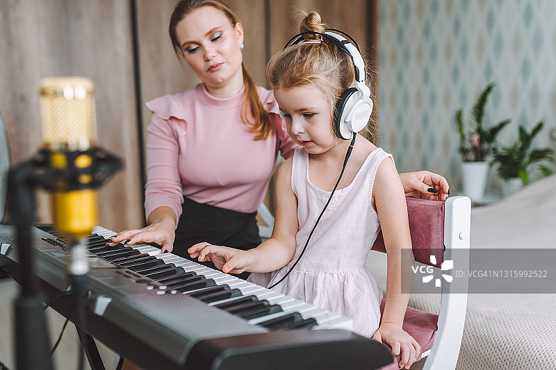 金发小女孩在家中与老师一起上音乐课图片素材