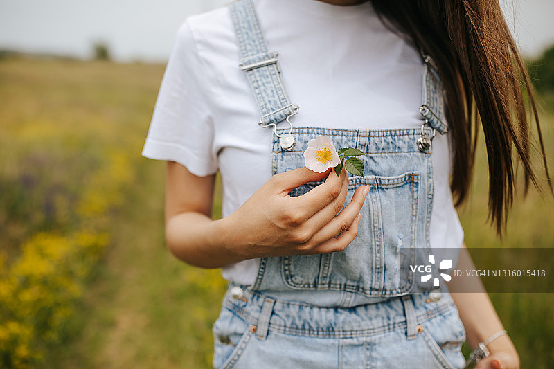 年轻女人将花朵放进口袋图片素材