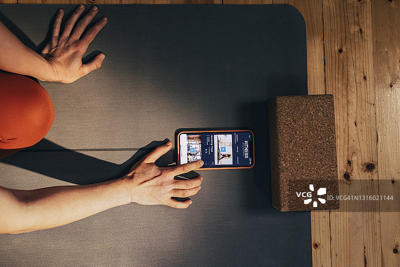 在家锻炼：年轻白人女性在智能手机上滑动健身应用程序图片素材