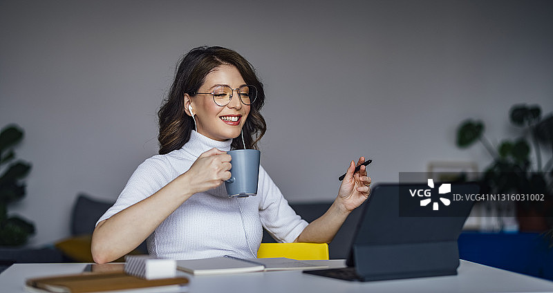 微笑的女商人拿着咖啡杯在办公桌旁图片素材