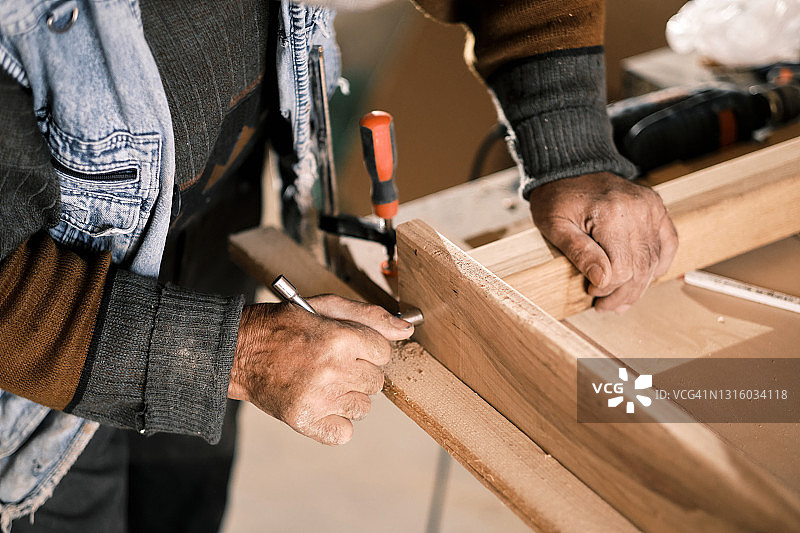 一位年长的男性木匠在他的旧作坊里工作图片素材
