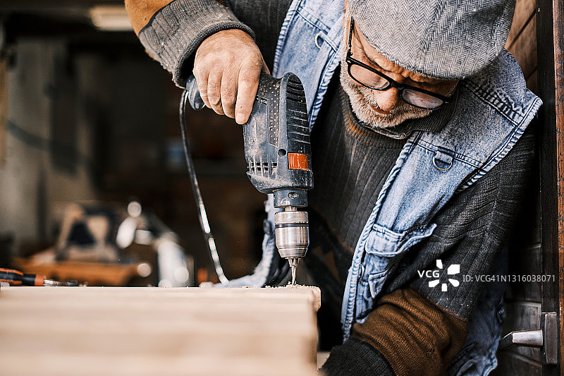 一位年长的男性木匠在他的旧作坊里工作图片素材