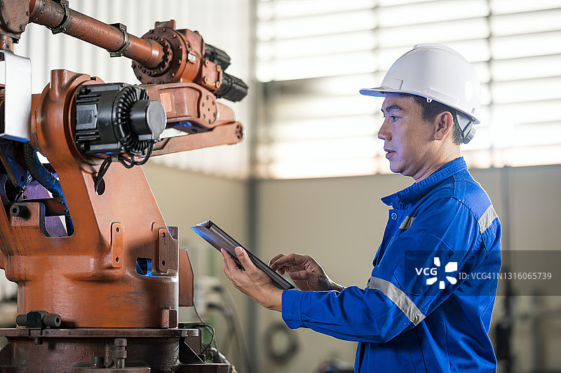 设备状态监测与预测性维护概念：亚洲年长的男性工业工程师在汽车行业工作，拥有机器人弧焊传感器和工业应用编程方面的专业知识。图片素材