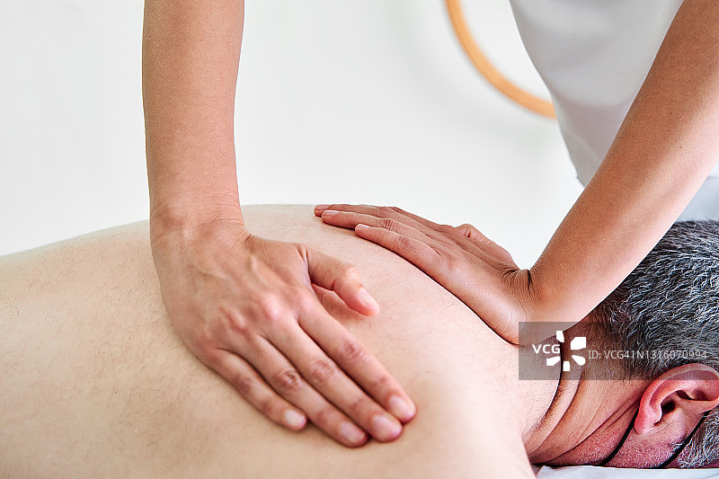 理疗师在诊所为病人进行背部按摩图片素材