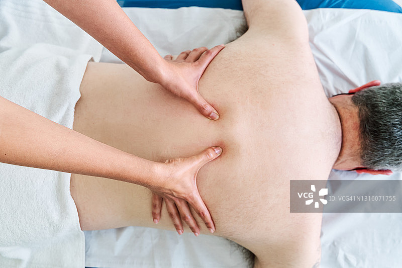 理疗师在诊所为病人进行背部按摩图片素材