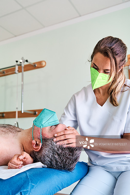 理疗师为诊所躺在担架上的顾客按摩颈部图片素材