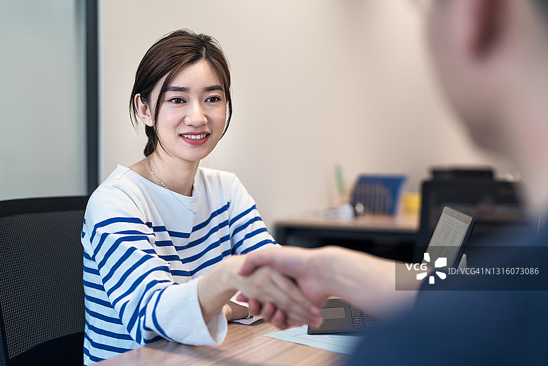 女商人与男商人在现代办公室握手图片素材