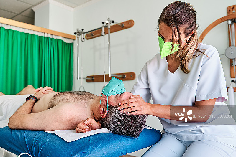 理疗师为诊所躺在担架上的顾客按摩颈部图片素材