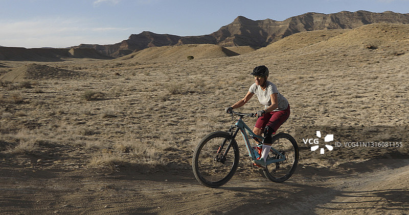 沿着沙漠小路骑行的女山地自行车手图片素材