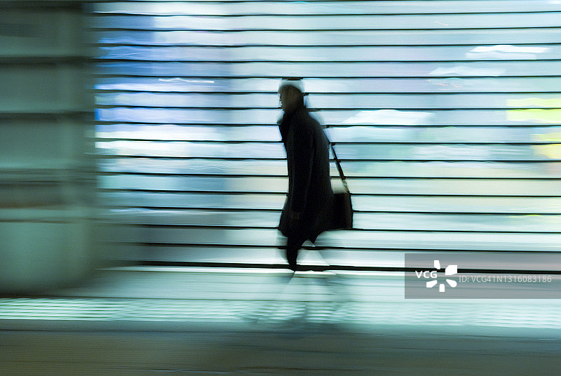 行人走在伦敦西区摄政街上，身后是灯火通明的商店橱窗图片素材