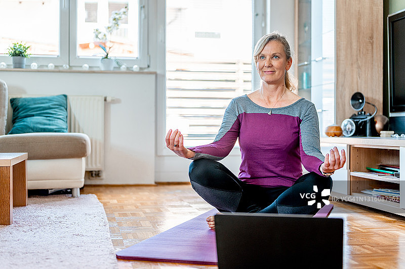 中年妇女在客厅里做瑜伽图片素材