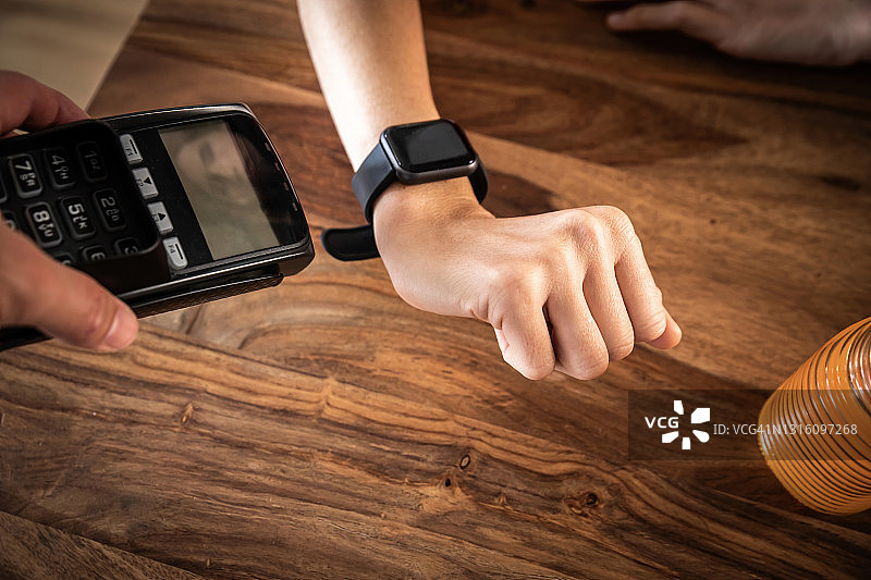在餐厅用智能手表非接触式支付的女人图片素材