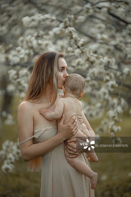 在夏日花园里拥抱的年轻母亲和女婴，家庭度假图片素材