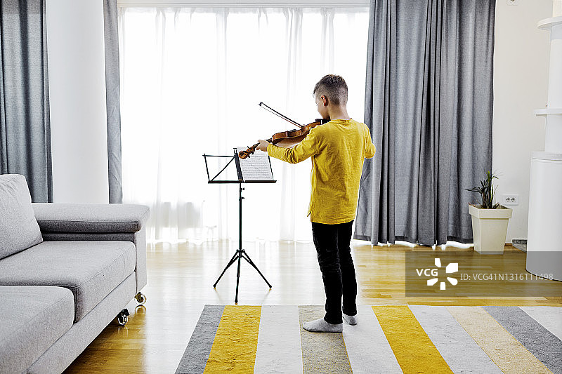 男孩在房间里拉小提琴图片素材