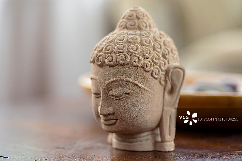 木桌上的装饰砂岩佛头雕像，象征东方宗教图片素材