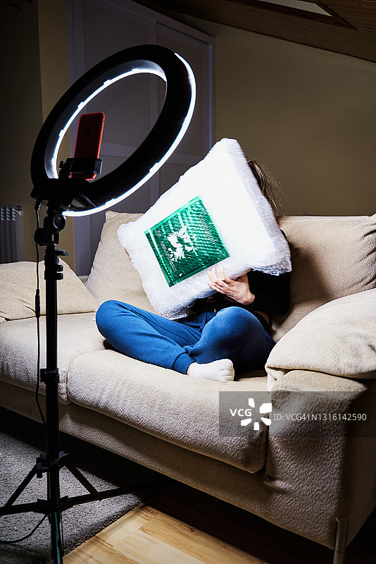 年轻的青少年女孩用手机在环形补光灯下拍摄图片素材