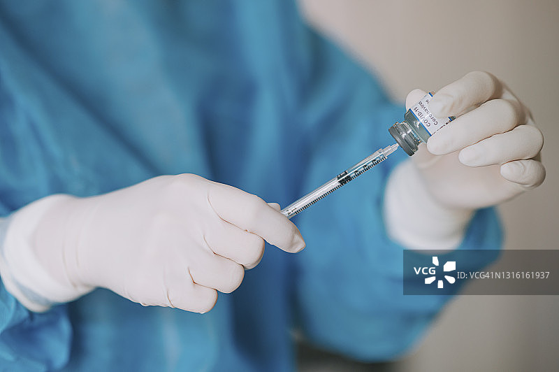 戴着PPE防护服和外科手套的亚裔女医生准备接种新冠疫苗图片素材