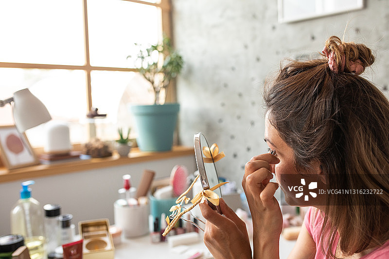 女人在家美容时用镊子拔眉毛图片素材