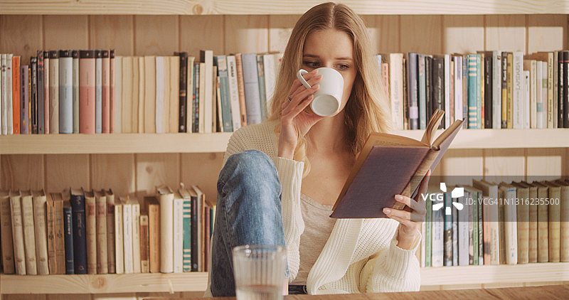 年轻女人在舒适的客厅里喝咖啡阅读放松图片素材