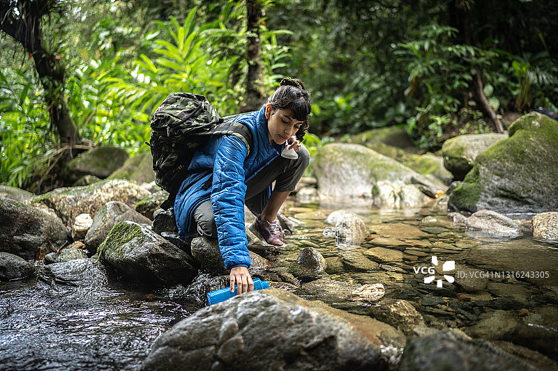 年轻女子从河里装水图片素材
