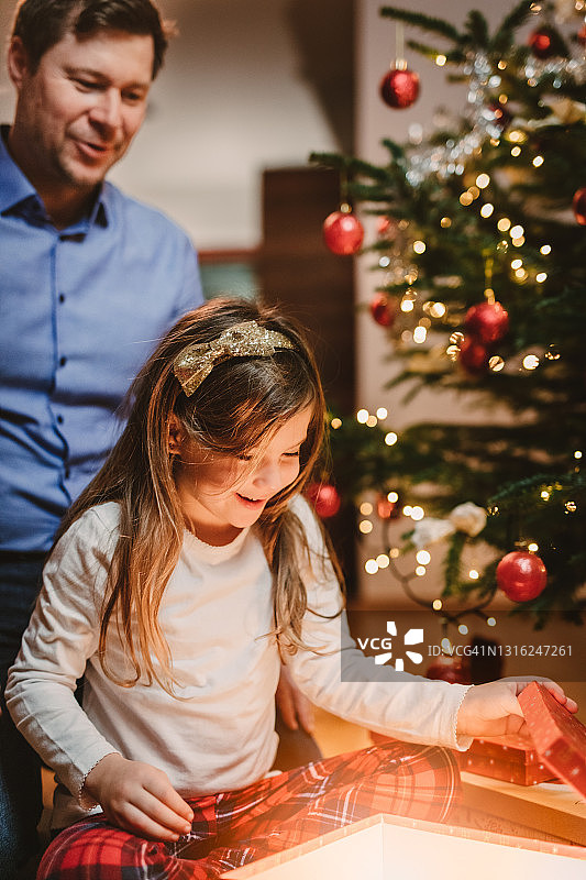 父亲和兴奋的女儿打开她的圣诞礼物图片素材