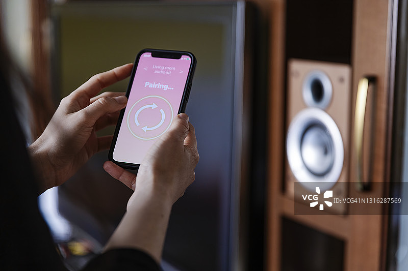 用智能手机和智能立体声扬声器听音乐的人图片素材