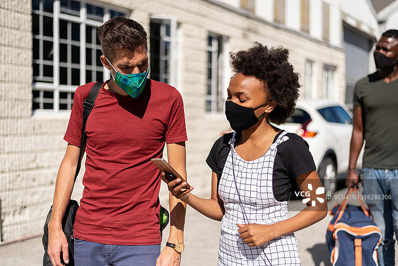 戴口罩的年轻男人和女人在看手机图片素材