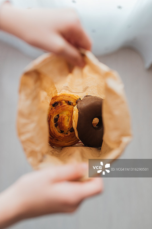 一个拿着装满面包纸袋的女孩的俯视图。可以看到里面的面包图片素材