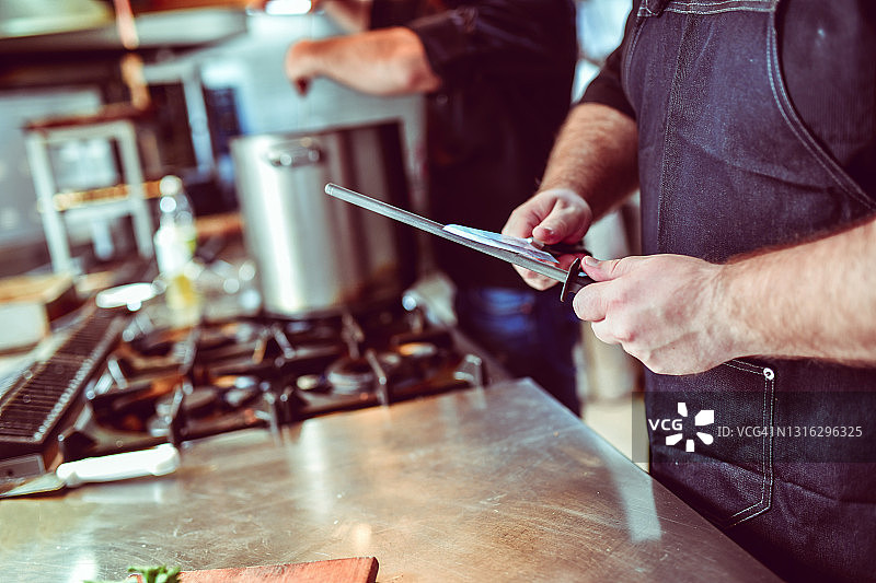 专业厨师在现代厨房磨刀图片素材