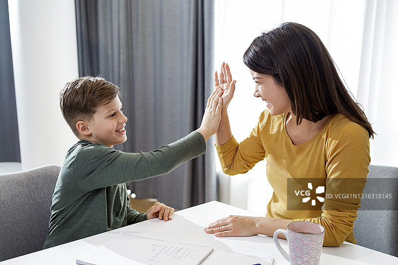 母亲教儿子做作业并帮助他图片素材