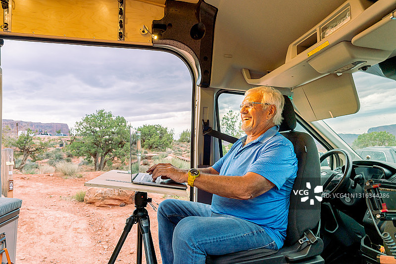 快乐的老年男人在露营旅行、露营车、房车生活时远程工作图片素材
