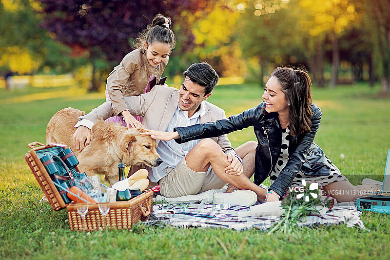幸福的一家人在公园里和他们的狗玩耍图片素材
