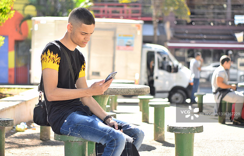在公共广场使用手机的年轻男人图片素材