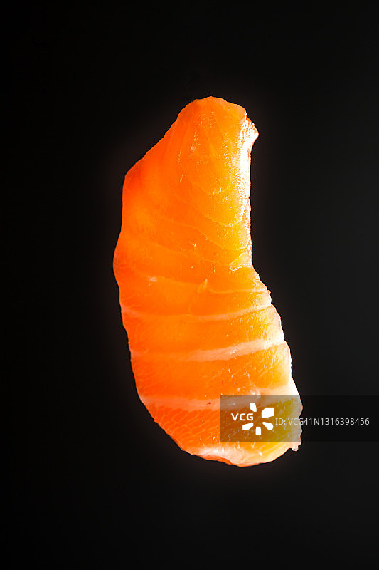 黑色背景中飞在空中的三文鱼片图片素材