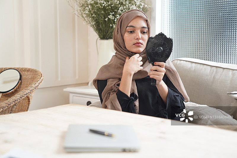 美丽的穆斯林年轻女子在家照镜子图片素材