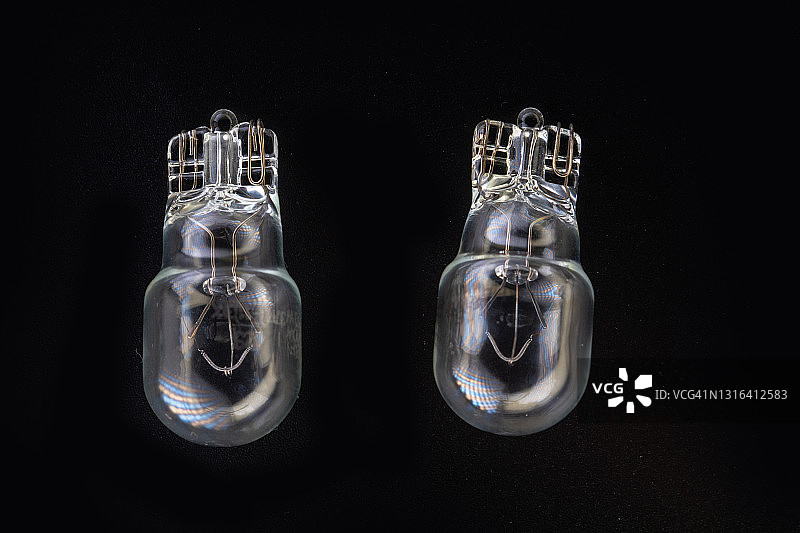 汽车经典卤素灯泡，灯丝、玻璃和金属材质，高能耗，黑色背景特写，留白区域，W10W图片素材