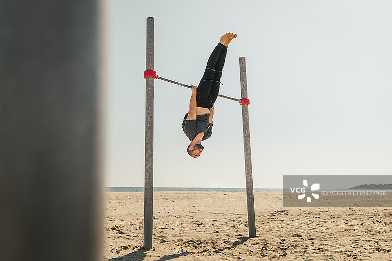 男人在海滩上练习单杠图片素材