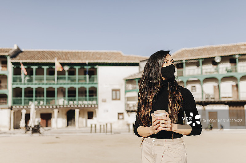 女人戴口罩在乡村拿着咖啡杯图片素材