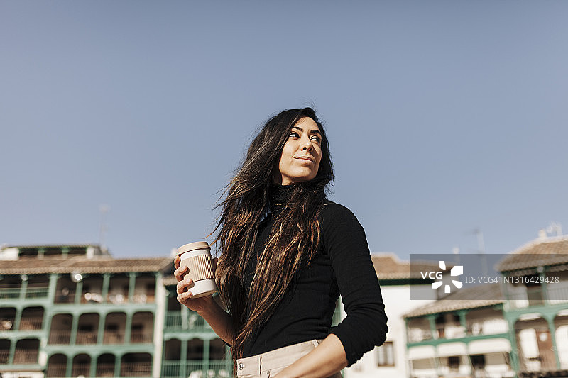 阳光明媚的日子里手捧咖啡杯的美丽女人图片素材