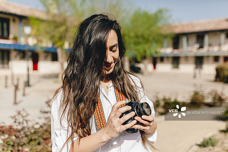 在阳光明媚的日子里拿着相机的微笑的女游客图片素材