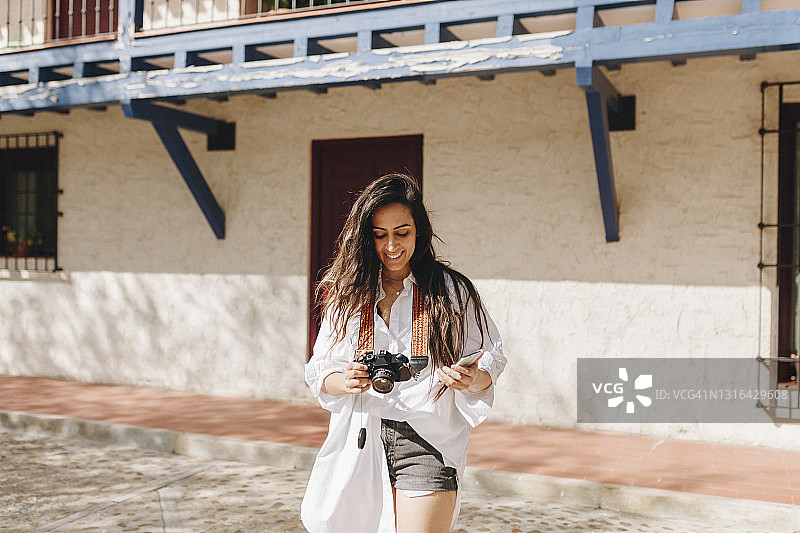 站在村庄的美丽女子正在检查相机图片素材