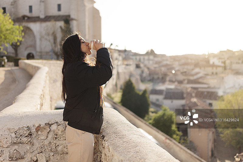 年轻女人站在屋顶喝咖啡图片素材